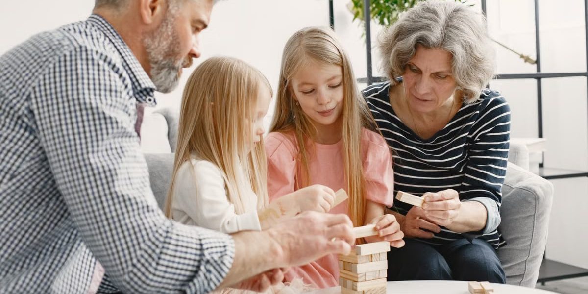 A family enjoying time together playing a block stacking game in their living room.