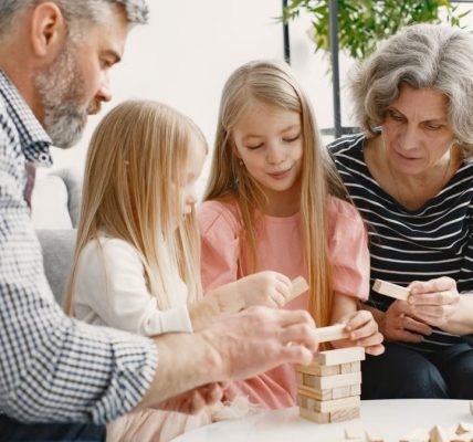 A family enjoying time together playing a block stacking game in their living room.