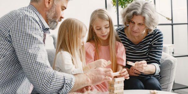 A family enjoying time together playing a block stacking game in their living room.